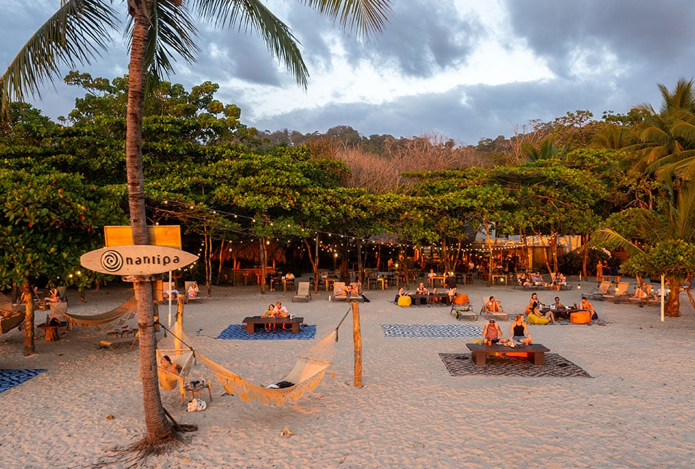 Beachfront dining at sunset under string lights